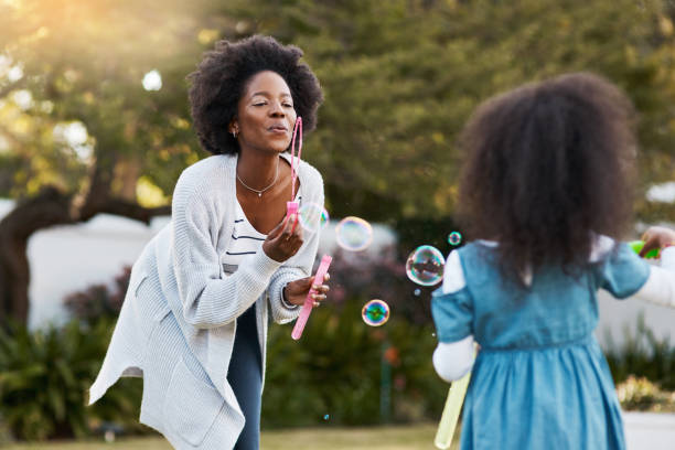 même maman se sent encore comme un gamin - bubble wand child outdoors bubble photos et images de collection