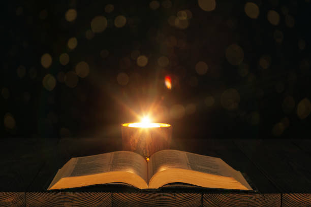 istock bible on the table in the light of a candle 1130445949