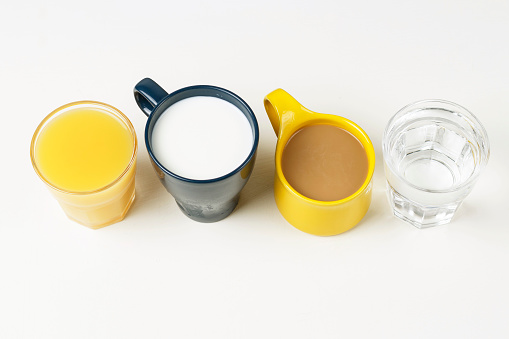 Coffee and other drinks in colorful cups on a white background, top view