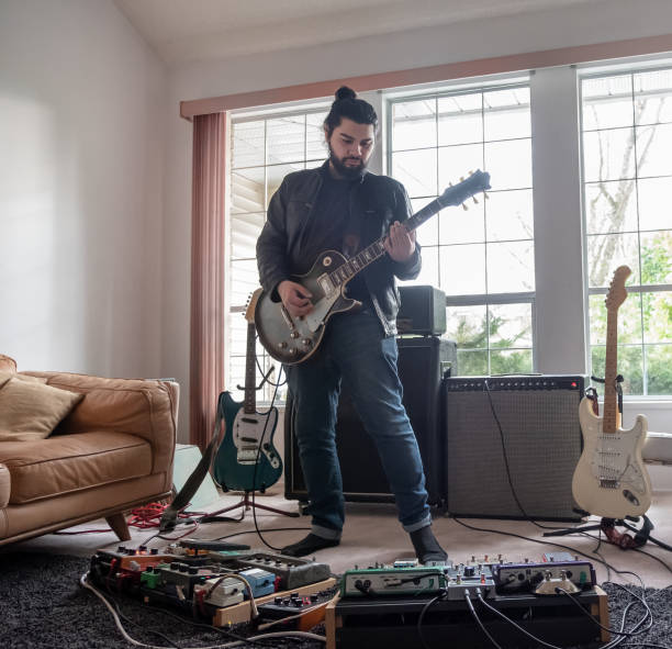 musiker, spielt e-gitarre mit sound-effekte pedale, wohnzimmer - guitar pedal stock-fotos und bilder