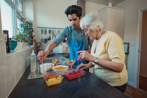 fare composta di frutta con nonna - grandmother senior adult family domestic kitchen foto e immagini stock