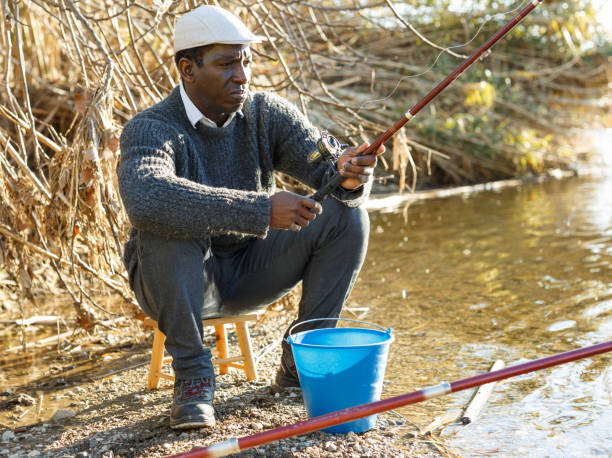 istock Positive fisherman sitting near river 1130453159