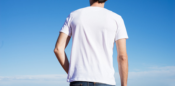 Young man wearing white t-shirt. Blue sky on background