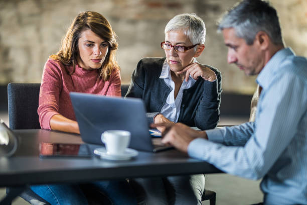 istock Senior mother and daughter using laptop with real estate agent. 1130454003