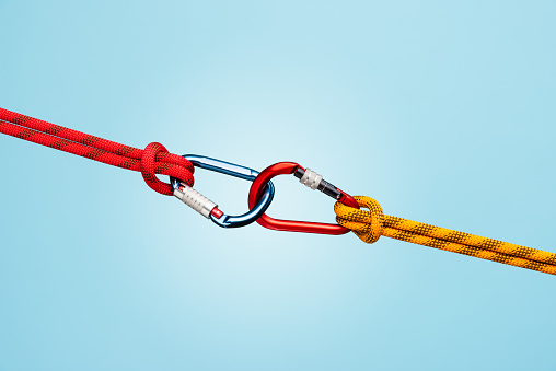 Strong connection with two locked carabiners and climbing rope on blue background