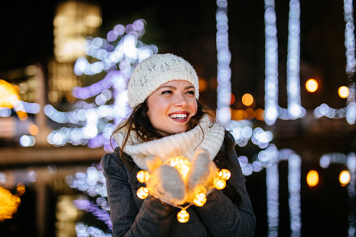 Young woman holding Christmas lights