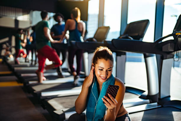 istock Woman using phone while resting from exercising at gym 1130455742
