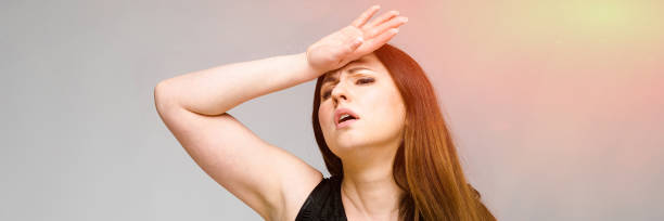 istock Emotional pretty confident plus size model standing in studio having headache on gray background 1130458100