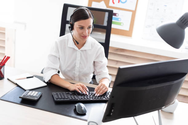 istock A young girl in headphones with a microphone sitting at a computer table. 1130458193