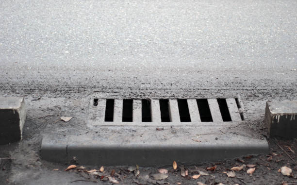 Sewer by footpath. Stormwater street drain stock photo