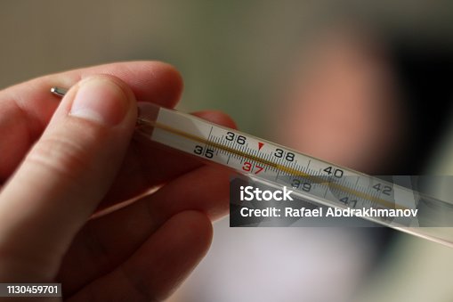 istock An alcohol thermometer shows a temperature of 37.9 on a blurred background of a sick girl lying on a bed. Check the temperature. Fever, illness, chills, care. 1130459701