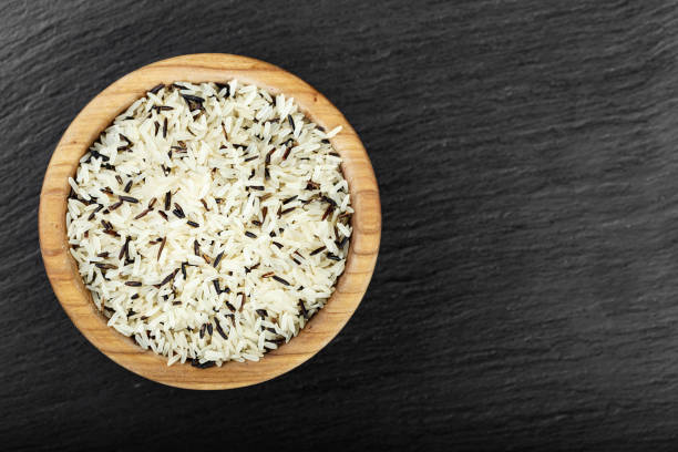 riz sauvage noir et blanc dans une plaque de bois sur un fond en bois. - rice black wild rice dry photos et images de collection