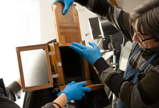Photographer sets an old large format camera with photographic plate chassis, before the shooting.