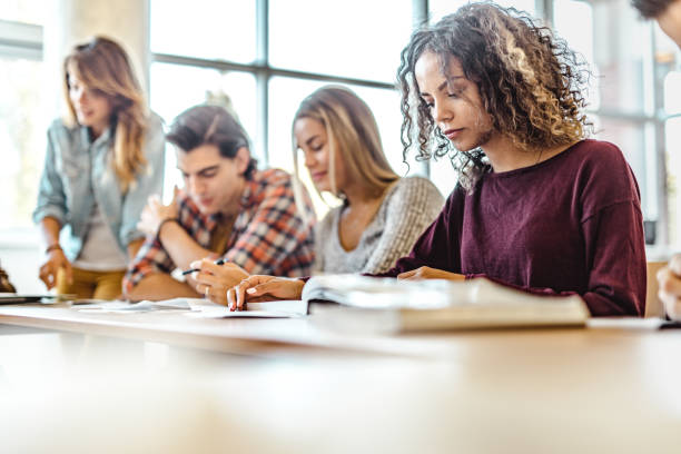 istock Concentrated college student reading a book on a class. 1130461599