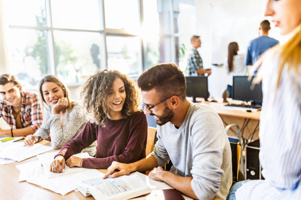 istock Happy college students talking while reading books in the classroom. 1130462197