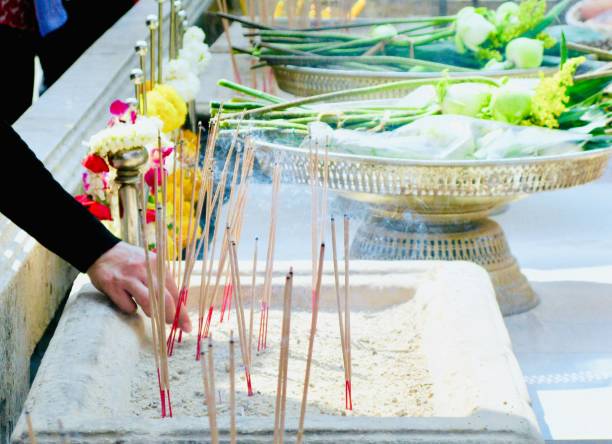 Hand Putting Burned Joss Sticks in Incense Burner in The Temple. People Use to Worship, Pay Respect and Make Merit with The Buddha.