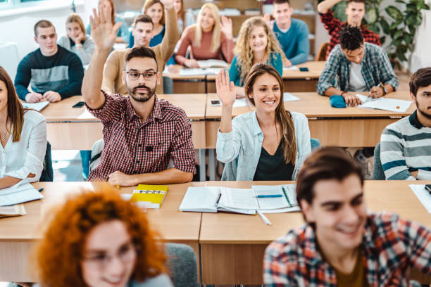 istock Large group of students raising hands during a class in the classroom. 1130463730