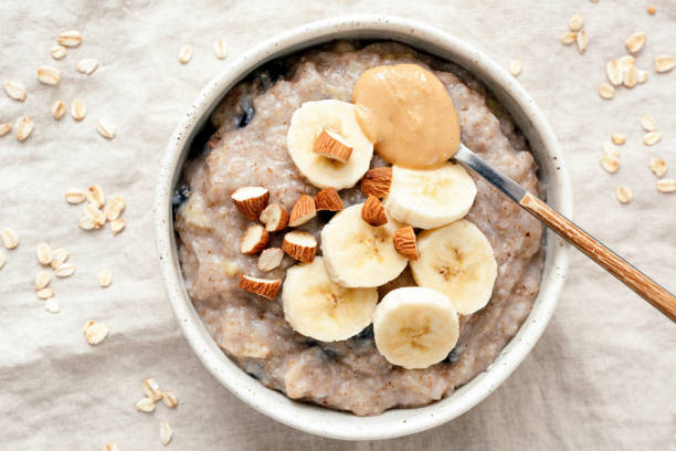 tazón de fuente de gachas de avena con plátano y mantequilla de maní - porridge fotografías e imágenes de stock