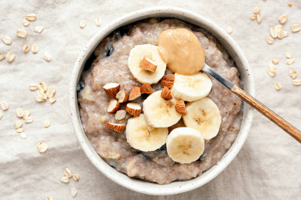 ciotola di porridge di farina d'avena con banana e burro di arachidi - porridge foto e immagini stock
