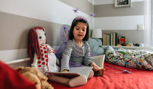 istock Girl disguised as a butterfly teaching her doll to read 1130467547