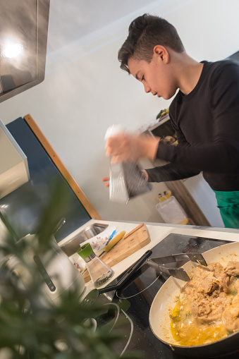 Teenager Boy Preparing Chicken Curry in Domestic Kitchen