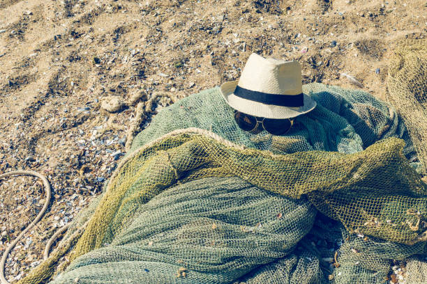 istock Hat and sunglasses lie on a fishing net on a sandy seashore 1130470242