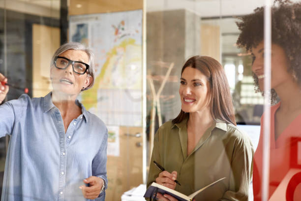 istock Female colleagues discussing plan on glass wall 1130470307
