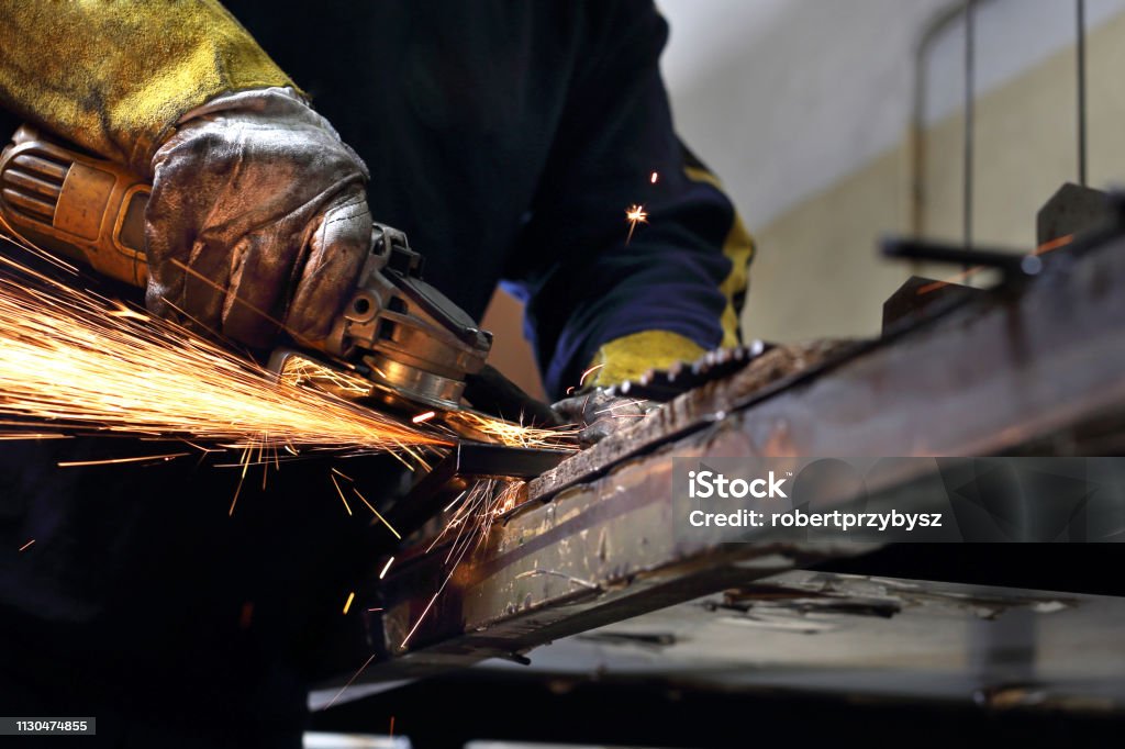 Grinding. The man polishes metal rods. Workshop. The worker polishes the metal. Locksmith Stock Photo