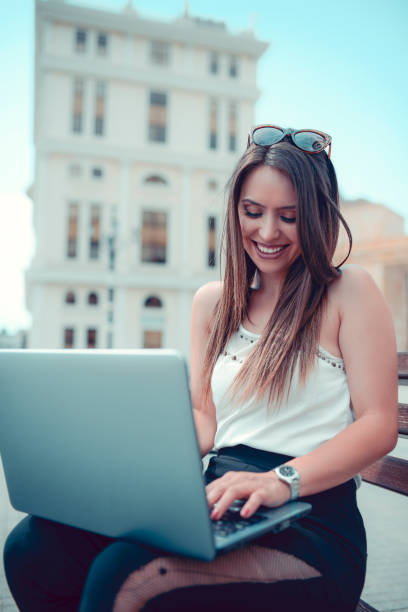 istock Cute Female Freelancer Working On Laptop While Relaxing On Bench In City Center 1130478670