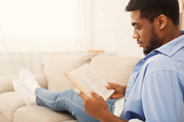 estudante do sexo masculino preto lendo o livro em casa - male education college student nerd - fotografias e filmes do acervo