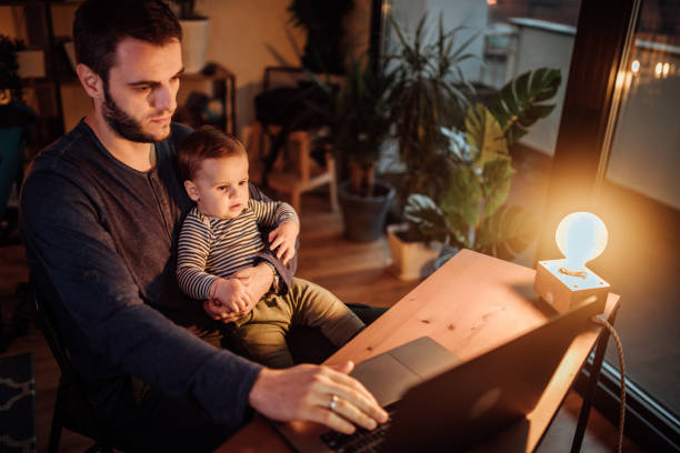 istock Dad working late at night and holding his baby son 1130479743