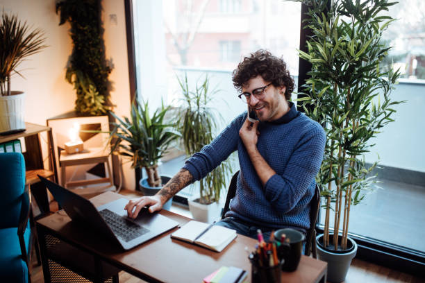 istock Young man talking on the phone in his home office 1130480374