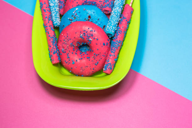 Glazed donuts with sprinkles and candy sticks on colorful background