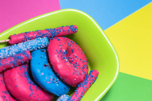 Glazed donuts with sprinkles and candy sticks on colorful background