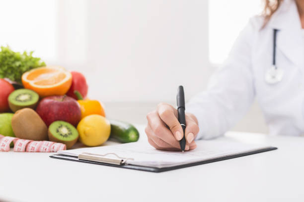 Doctor nutritionist writing on paperwork in office Paperwork. Doctor nutritionist writing on paperwork in office, filling patient health history, copy space nutritionist stock pictures, royalty-free photos & images