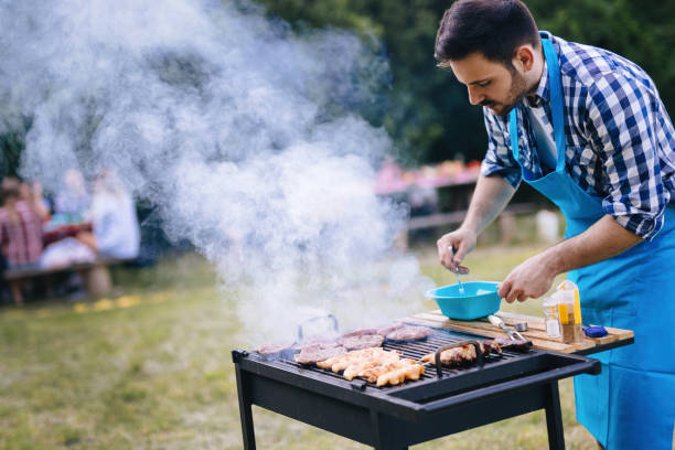 istock Handsome male preparing barbecue with happy friends 1130491393