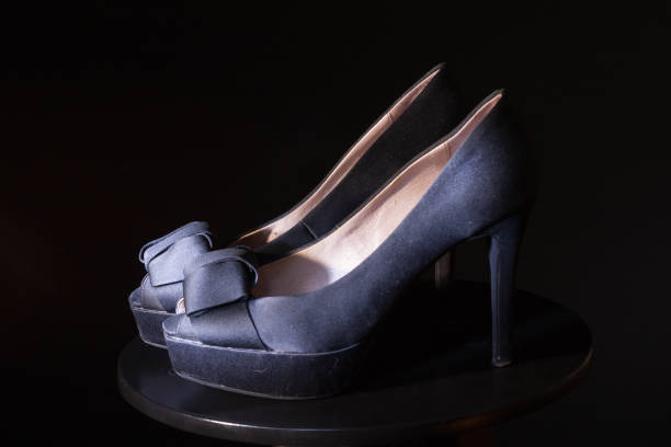 istock Black ladies stiletto heel pump with bow on black background. 1130495039