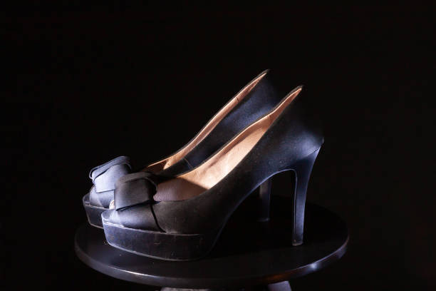 istock Black ladies stiletto heel pump with bow on black background. 1130495089