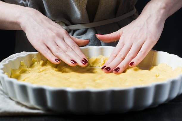 istock Chef rolls out the dough in a baking dish, cooking. Side view, black background, close up. 1130495191