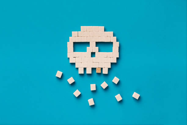 Sweets ruin teeth. Skull made from sugar cubes with brown lump sugar expressing caries and decay on blue background