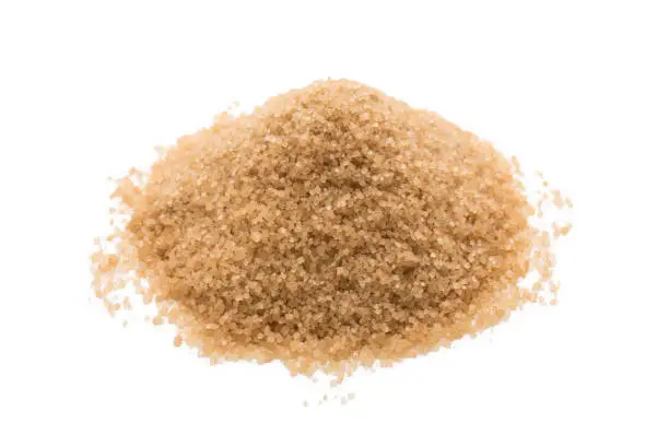 Heap of brown cane sugar isolated on white background