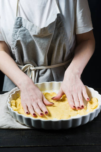 istock Chef rolls out the dough in a baking dish, cooking. Side view, black background, close up. 1130495854