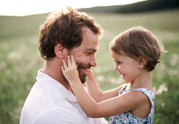 giovane padre in natura che tiene in braccio la figlia piccola. - clothing love family with one child parent foto e immagini stock