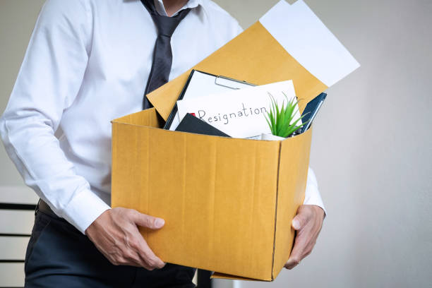 istock Midsection Of Businessman Carrying Documents In Cardboard Box While Standing Against Wall In Office 1130500392