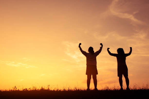 istock Silhouette Friends Flexing Muscles While Standing On Field Against Sky During Sunset 1130500493