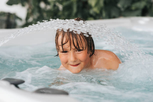 Handsome little boy enjoying warm water in hot tub stock photo