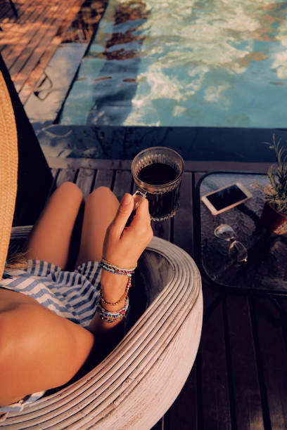 istock Girl using cellphone while lying on a swimming pool deck lounge bed. 1130503645