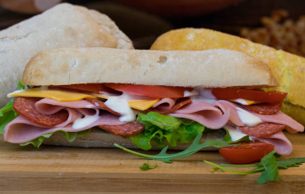 istock breads stacked on wooden surface. One filled with salad & sliced meats. 1130506139