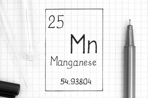 The Periodic table of elements. Handwriting chemical element Manganese Mn with black pen, test tube and pipette. Close-up.