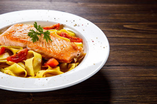 istock Pasta with salmon and vegetables on wooden background 1130506275